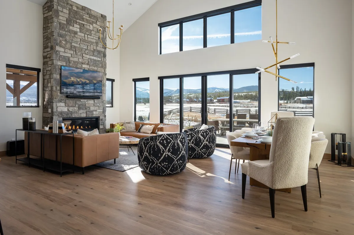 A cozy dining and living area with a stone fireplace, large windows, a wooden dining table, and comfortable seating. The setting is perfect for family dinners, holiday gatherings, and relaxing evenings, enhanced by soft natural light and warm décor.