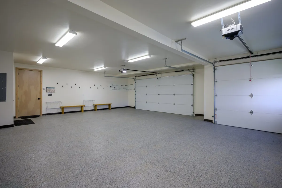 A functional garage interior featuring practical gear storage solutions, a workbench, and hooks for organizing equipment. The space is clean, well-lit, and ready for adventure gear in any season.