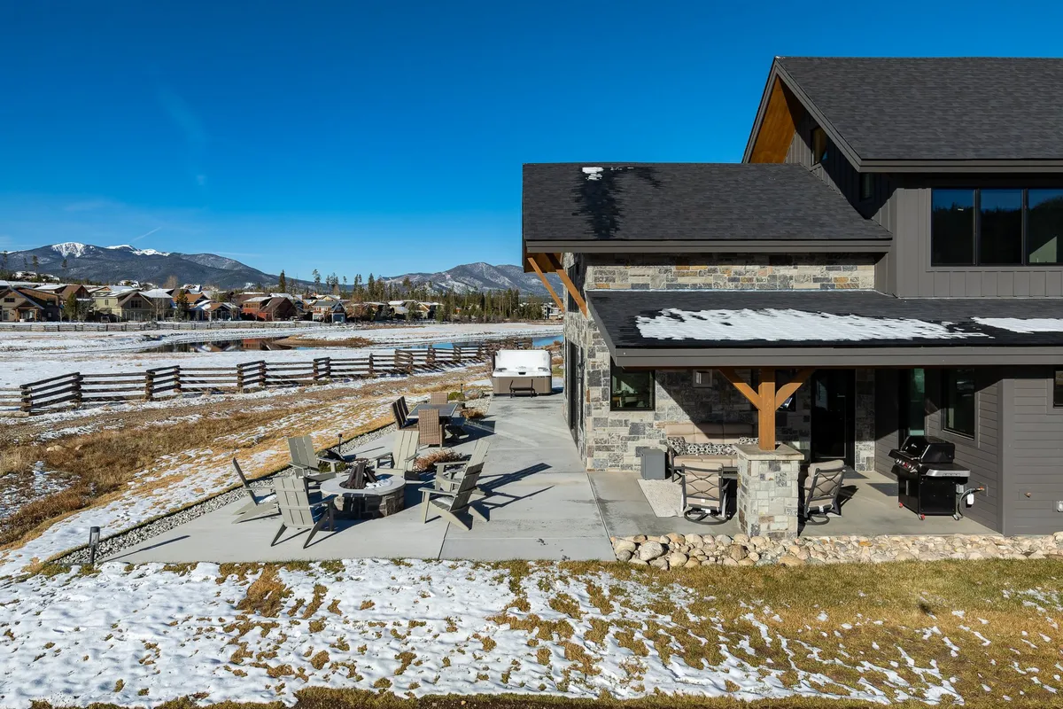 A spacious stone patio with comfortable outdoor seating, set against a dramatic mountain backdrop. The setup is ideal for outdoor dining or hosting gatherings, and the scene exudes serenity and luxury.