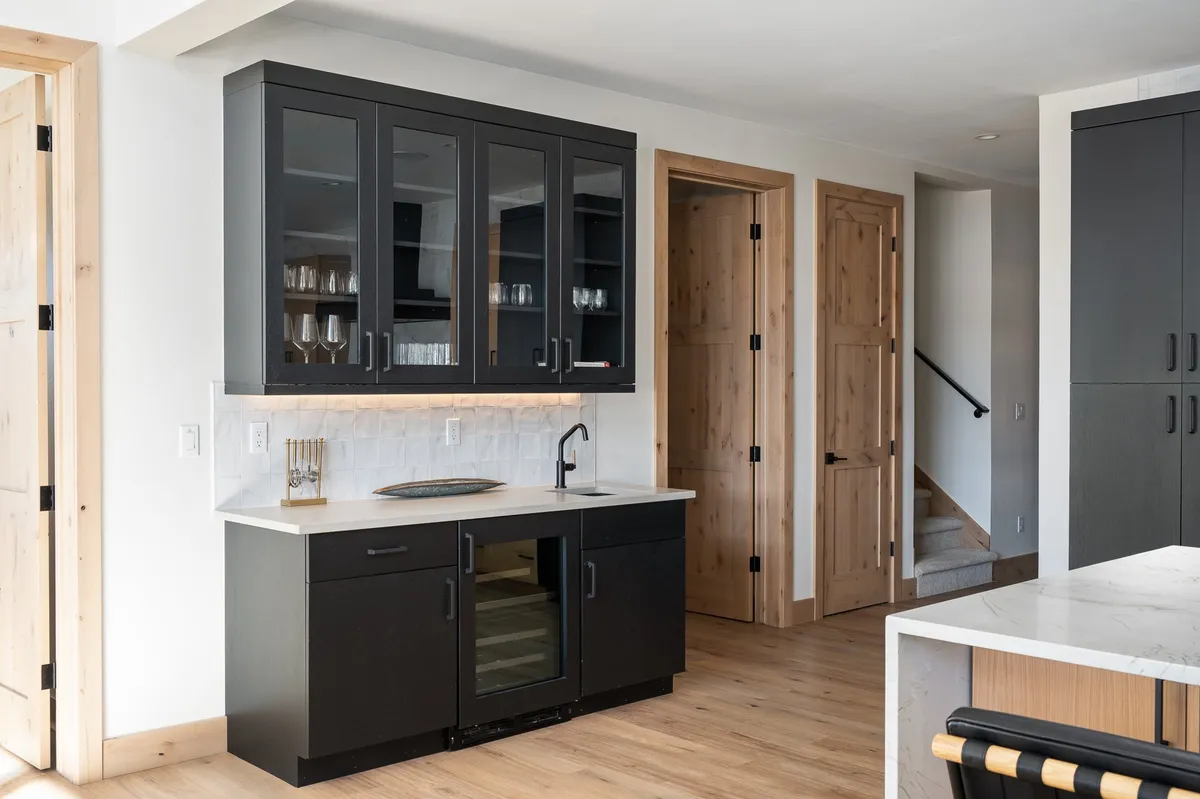 A sleek kitchenette setup with black cabinetry, modern glassware, and a contemporary faucet. The countertop space is ideal for preparing snacks and drinks, supporting easy entertaining and quick refreshments.